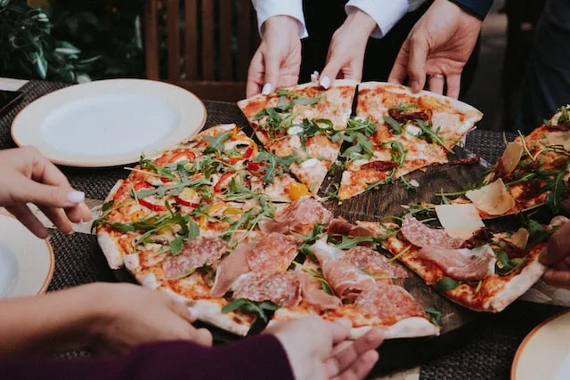 Person holding pizza on white ceramic plate