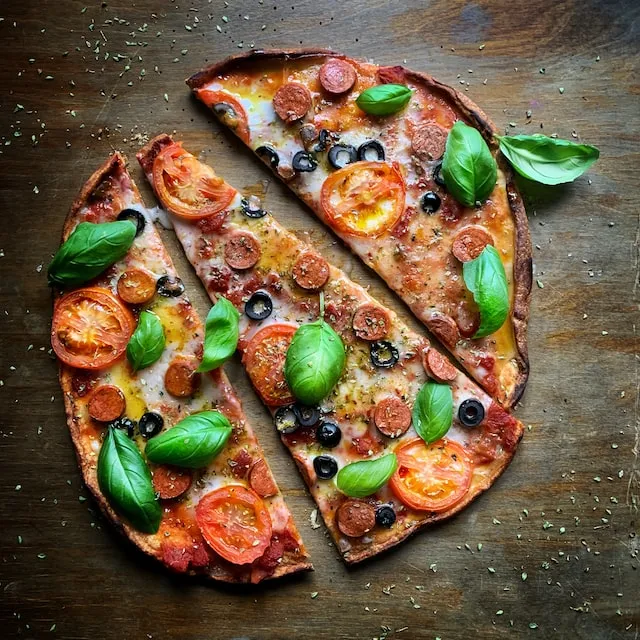 Pizza with green leaves on brown wooden table