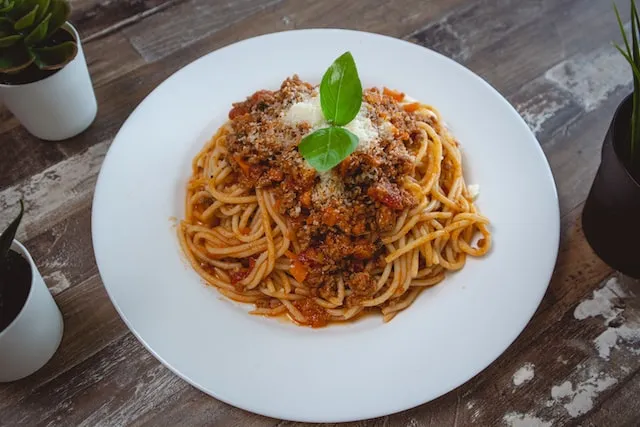 Pasta dish on white plate with basil leaves