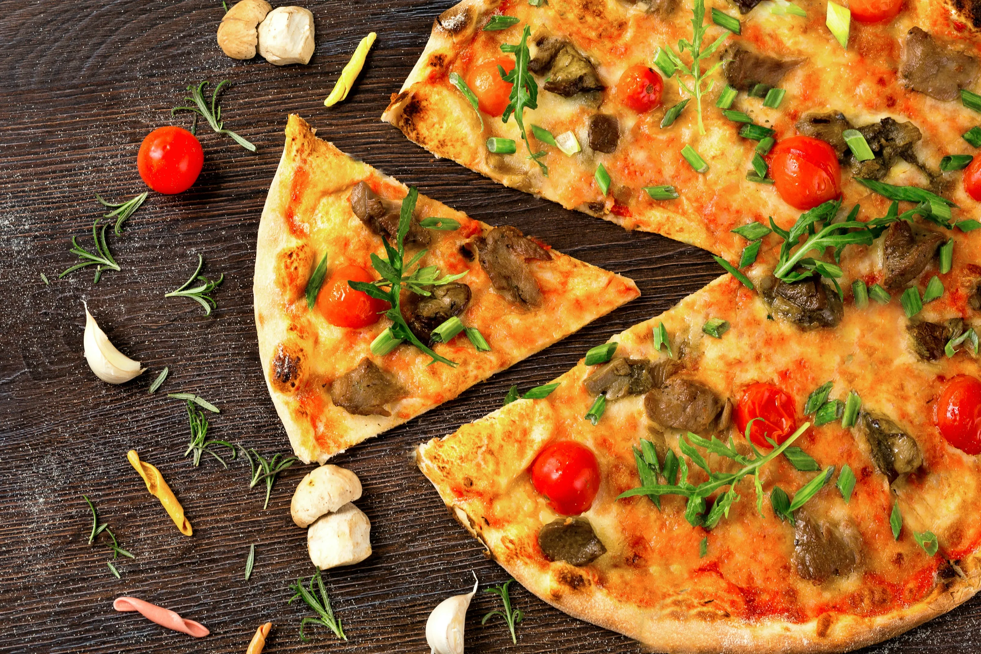 Pizza with tomato and green leaves on white ceramic plate
