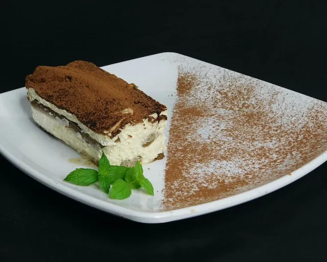Tiramisu on white plate with mint leaf